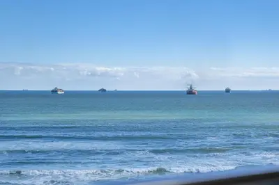 a group of cargo ships in the ocean at Portico 704 in Bloubergstrand