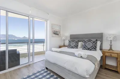 a bedroom with a large bed with a view of the ocean at Portico 704 in Bloubergstrand