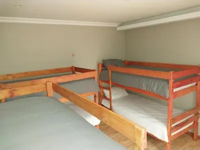 a room with three bunk beds in it at Serenity Shores Backpackers in Cape Town
