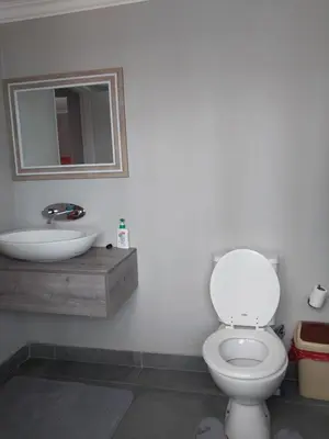 a bathroom with a white toilet and a sink at Serenity Shores Backpackers in Cape Town