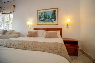 a bedroom with a white bed with a picture on the wall at Broadway Boston in Cape Town
