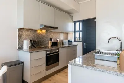 a kitchen with white cabinets and a sink at Burmeister 606 - Top Floor 2 Bedroom Apartment with Ocean Views - Onsite Parking in Cape Town