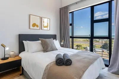 a bedroom with a bed with a large window at Burmeister 606 - Top Floor 2 Bedroom Apartment with Ocean Views - Onsite Parking in Cape Town