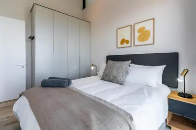 a bedroom with a large bed with white sheets at Burmeister 606 - Top Floor 2 Bedroom Apartment with Ocean Views - Onsite Parking in Cape Town