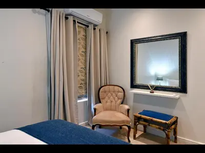 a bedroom with a bed and a chair and a mirror at Sunflower Villa in Franschhoek in Franschhoek