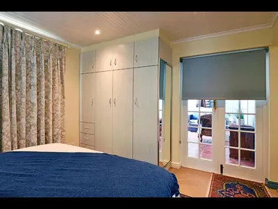 a bedroom with a blue bed and a large cabinet at Sunflower Villa in Franschhoek in Franschhoek
