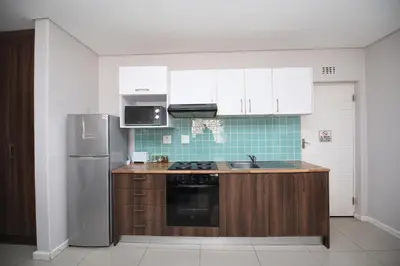 a kitchen with white cabinets and a stainless steel refrigerator at The Brookston in Cape Town