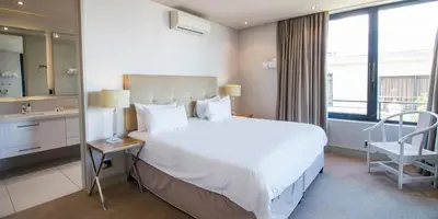 a bedroom with a large white bed and a chair at Harbour House Hotel - Le Paradis Apartments in Hermanus