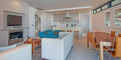 a living room with a couch and a dining room at Harbour House Hotel - Le Paradis Apartments in Hermanus