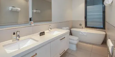 a bathroom with two sinks and a toilet and a mirror at Harbour House Hotel - Le Paradis Apartments in Hermanus