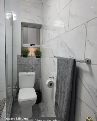 a white bathroom with a toilet and a window at Elite Escape in Cape Town