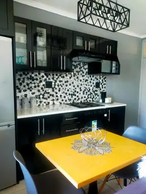 a kitchen with black cabinets and a yellow table at Elite Escape in Cape Town