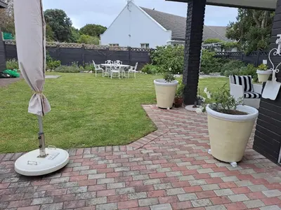 a patio with two large pots with plants in a yard at Milky Way in Hermanus