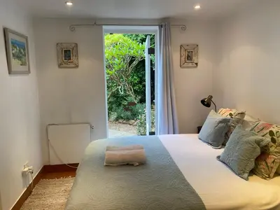 a bedroom with a large bed with a window at Tranquil Olive Tree Garden Apartment 2 in Cape Town