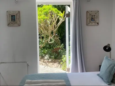 a bedroom with a bed and a door to a garden at Tranquil Olive Tree Garden Apartment 2 in Cape Town