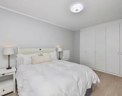 a white bedroom with a large bed with white cabinets at Capri On Lake 101 The Island Club in Cape Town