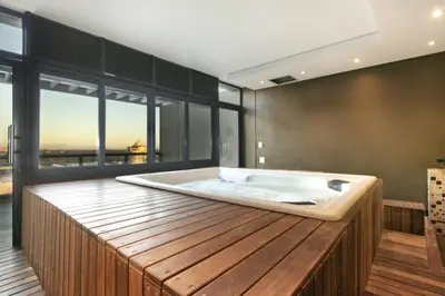 a large bath tub in a room with windows at Grand Penthouse / Backup Power / Stunning in Cape Town