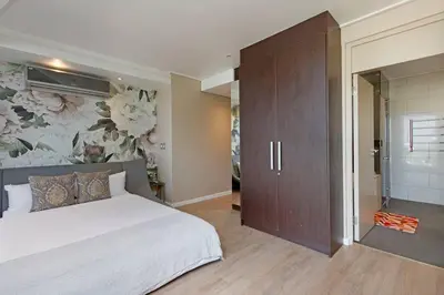 a bedroom with a large bed with a floral wallpaper at Grand Penthouse / Backup Power / Stunning in Cape Town