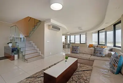 a living room with a couch and a staircase at Grand Penthouse / Backup Power / Stunning in Cape Town