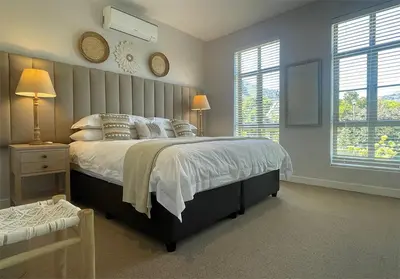 a bedroom with a large bed and two windows at Franschhoek Mountain Views in Franschhoek