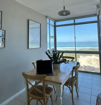 a dining room with a table with a laptop on it at Charming beachfront Strand apartment in Cape Town