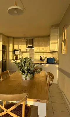 a kitchen with a wooden table with a vase of flowers at Charming beachfront Strand apartment in Cape Town