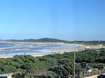 a beach with people on the sand and the water at Charming beachfront Strand apartment in Cape Town