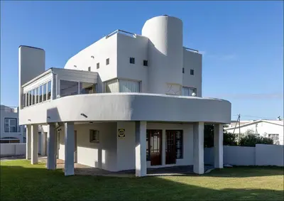 a large white building with the front entrance to it at Sunset Terrace in Hermanus