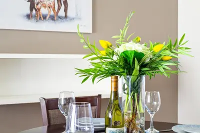 a table with a vase of flowers and wine glasses at Lagoon Beach 29A in Cape Town