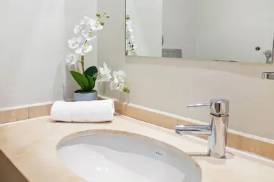a bathroom sink with a vase of flowers and a mirror at Lagoon Beach 29A in Cape Town