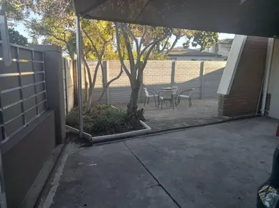 a patio with a tree and chairs and a fence at Two bedroom flatlet in Panorama in Cape Town