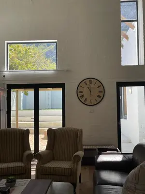a living room with a clock on the wall at Fynbos Feniks Family House in Voëlklip in Hermanus