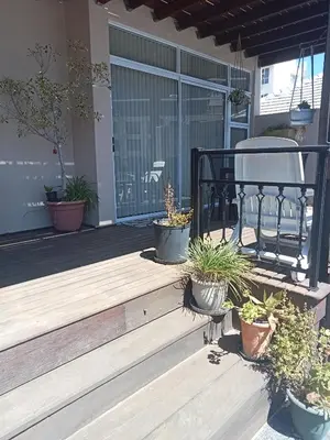 a porch with potted plants and a chair on it at Culemborg Court in Cape Town