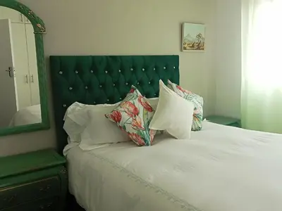 a bed with a green headboard and pillows on it at Culemborg Court in Cape Town