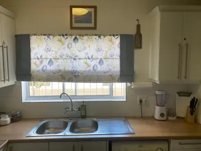 a kitchen with a sink and a window with a curtain at Culemborg Court in Cape Town