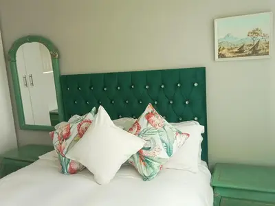 a bed with a green headboard and pillows on it at Culemborg Court in Cape Town