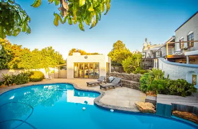 a backyard with a swimming pool and a house at Villa Luisa: Sun-filled hidden gem with Pool. in Cape Town