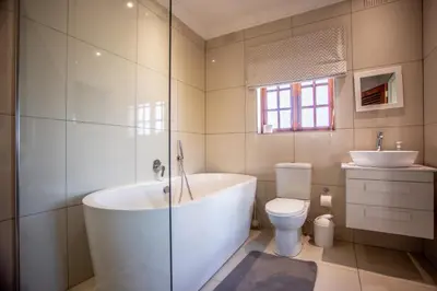 a bathroom with a tub and a toilet and a sink at Villa Luisa: Sun-filled hidden gem with Pool. in Cape Town