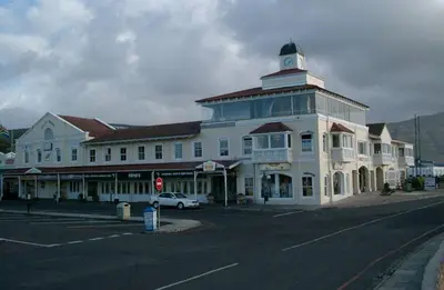 a large white building with a clock tower on a street at Hermanus Waterfront Apartment 12 in Hermanus