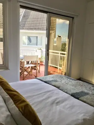 a bedroom with a bed and a view of a patio at Lala Panzi - Grotto Beach, Voëlklip in Hermanus