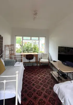 a room with two beds and a desk and a window at Lala Panzi - Grotto Beach, Voëlklip in Hermanus