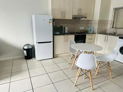 a kitchen with a white refrigerator and a table and chairs at Delightful Retreat in Parklands,Cape Farms,Cape Town in Cape Town