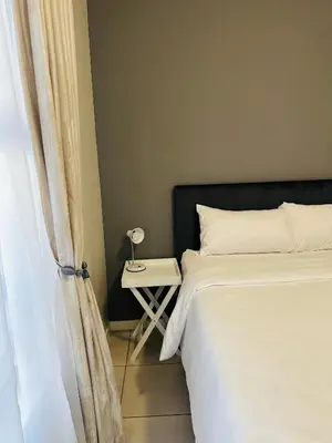 a bedroom with a bed and a side table with a lamp at Delightful Retreat in Parklands,Cape Farms,Cape Town in Cape Town