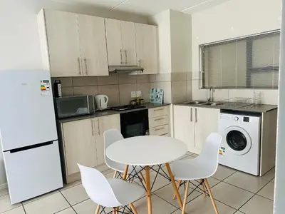 a kitchen with a white table and white appliances at Delightful Retreat in Parklands,Cape Farms,Cape Town in Cape Town