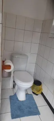 a bathroom with a white toilet and a blue rug at McSheyson Apartment - Deluxe in Cape Town