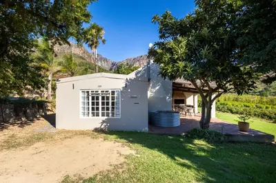 a small white shed with a tree in the yard at Dorpsig Cottage in Paarl