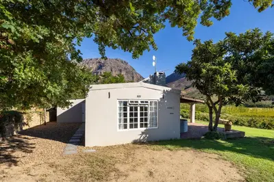 a small white building with a mountain in the background at Dorpsig Cottage in Paarl