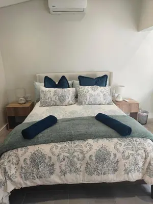 a bedroom with a large bed with blue pillows at Digital Nomad's Nest, Somerset West in Cape Town