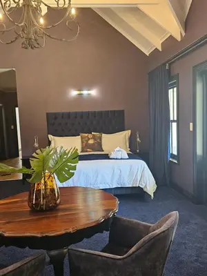 a bedroom with a bed and a table and chairs at Die Heerenhuys Guest Suites in Stellenbosch