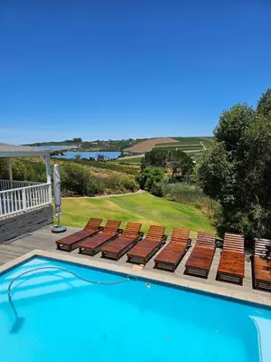 a swimming pool with lounge chairs and a view of the ocean at Die Heerenhuys Guest Suites in Stellenbosch
